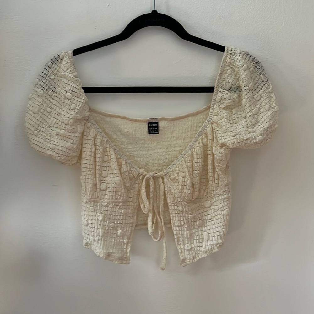 A trendy off white tie top. Has cool material. Size small.